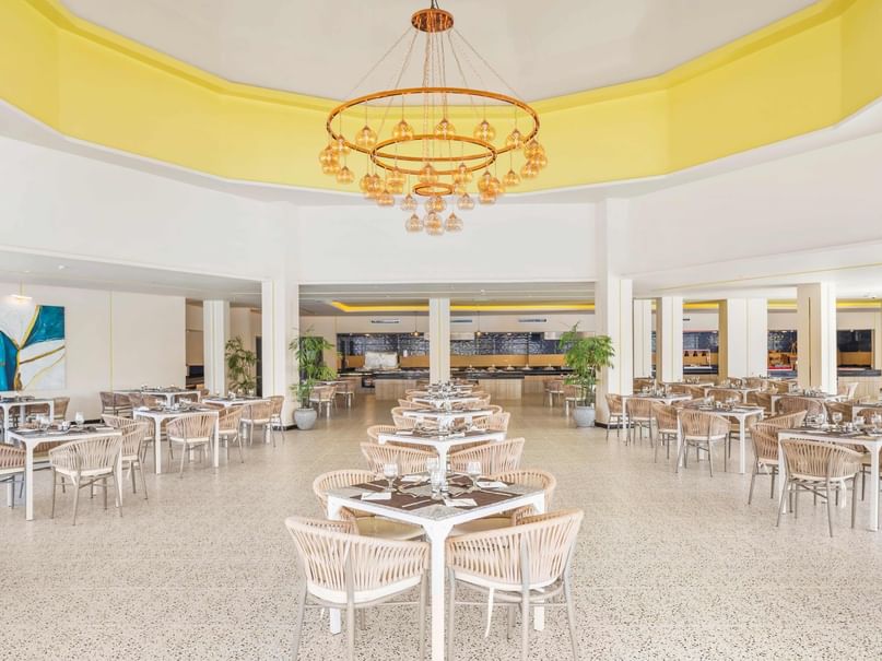 Elegant dining hall with white tables and chairs under a large chandelier at Pickalbatros Alf Leila Wa Leila Resort - Neverland Hurghada.