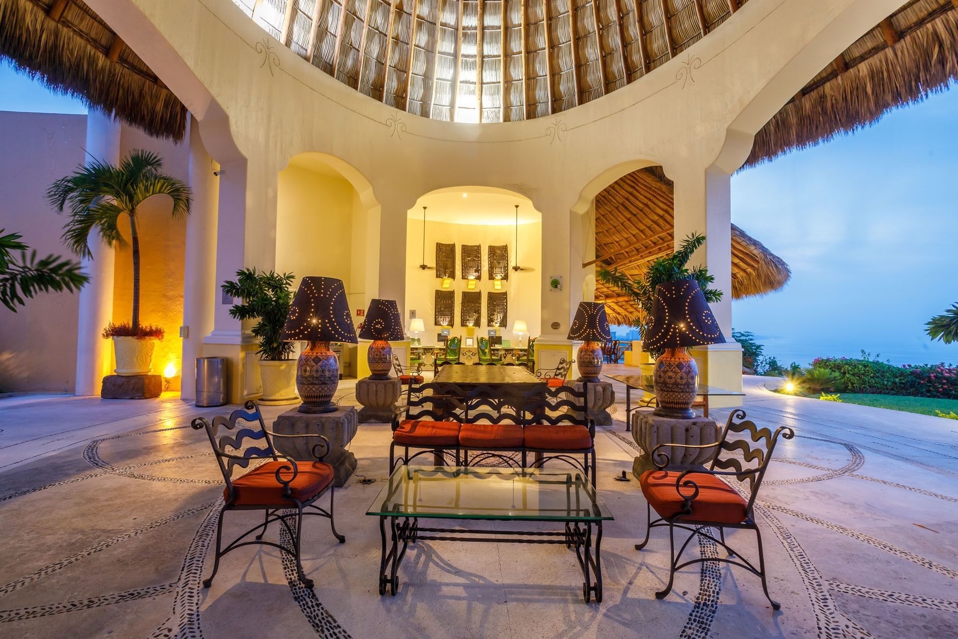 Spacious lounge area featuring glass tables and views of the ocean under a palapa roof at Quinta Real Acapulco