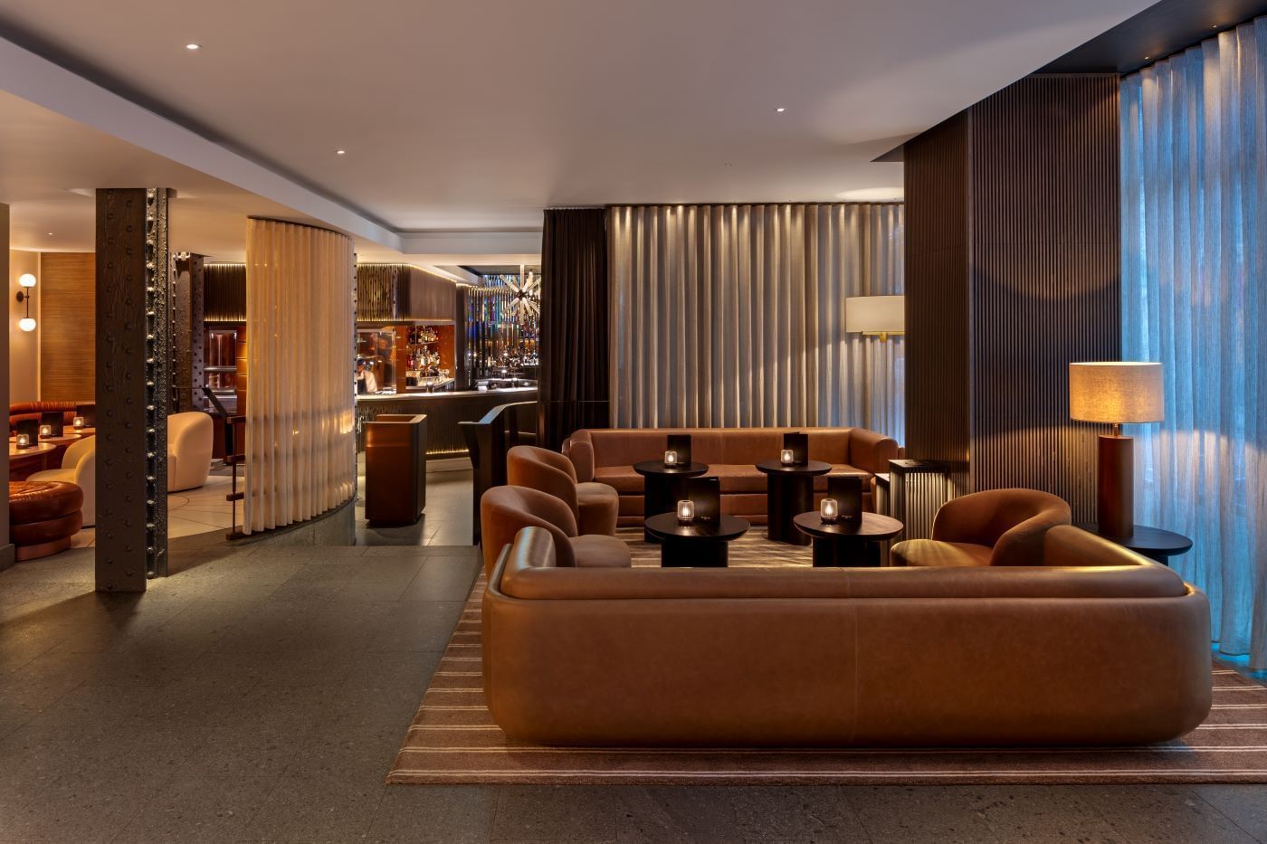 Elegant lounge area with couches, tables, and a bar at The May Fair Bar