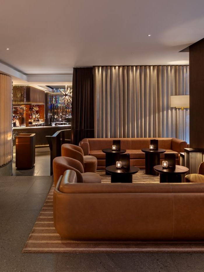 Elegant lounge area with couches, tables, and a bar at The May Fair Bar