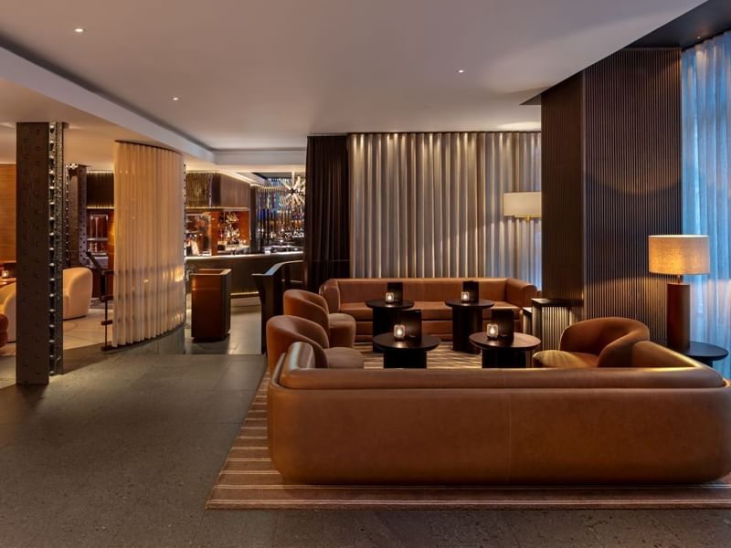 Elegant lounge area with couches, tables, and a bar at The May Fair Bar