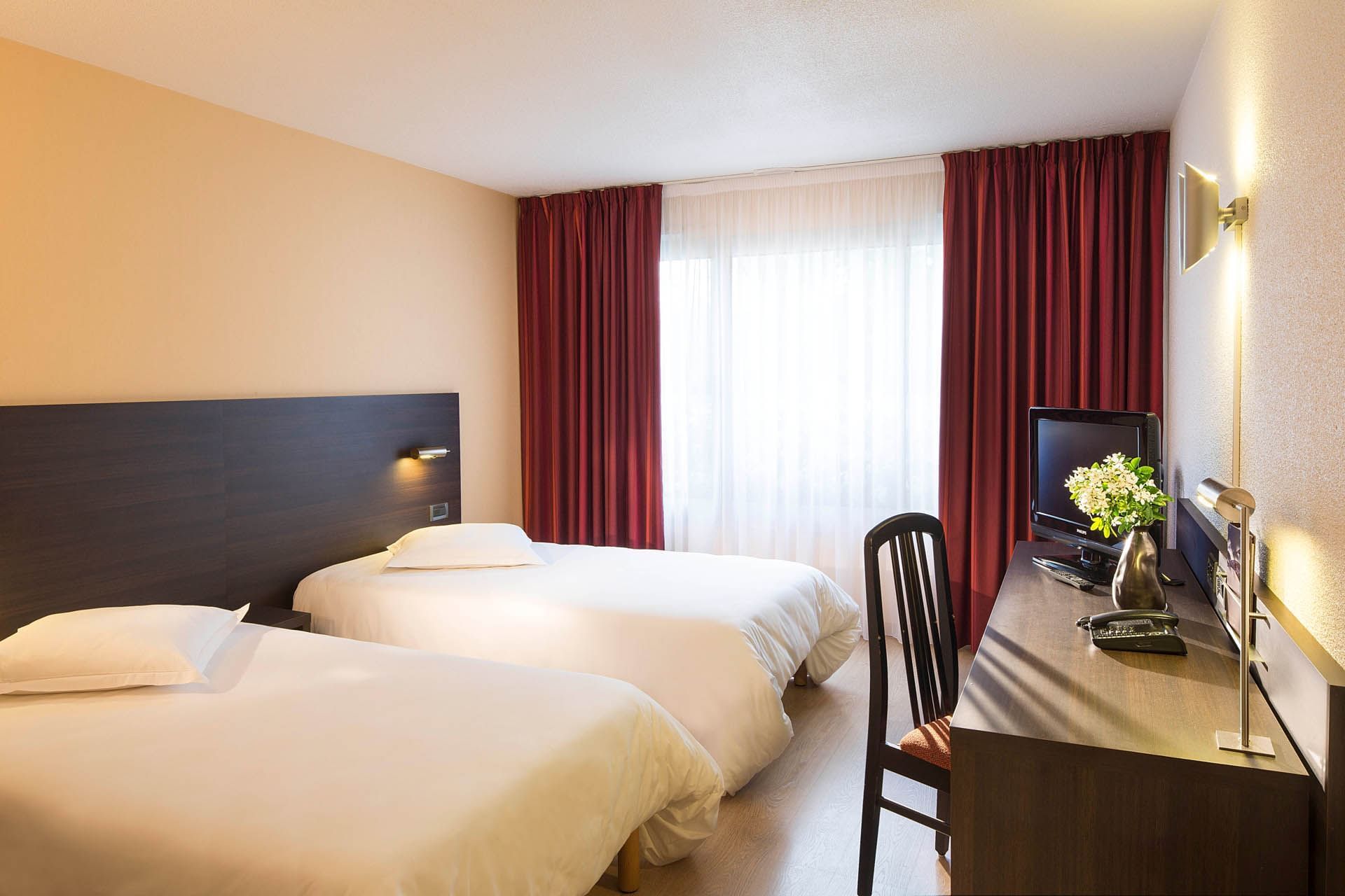 Deux lits et télévision dans une chambre à Escale Oceania Brest Aeroport