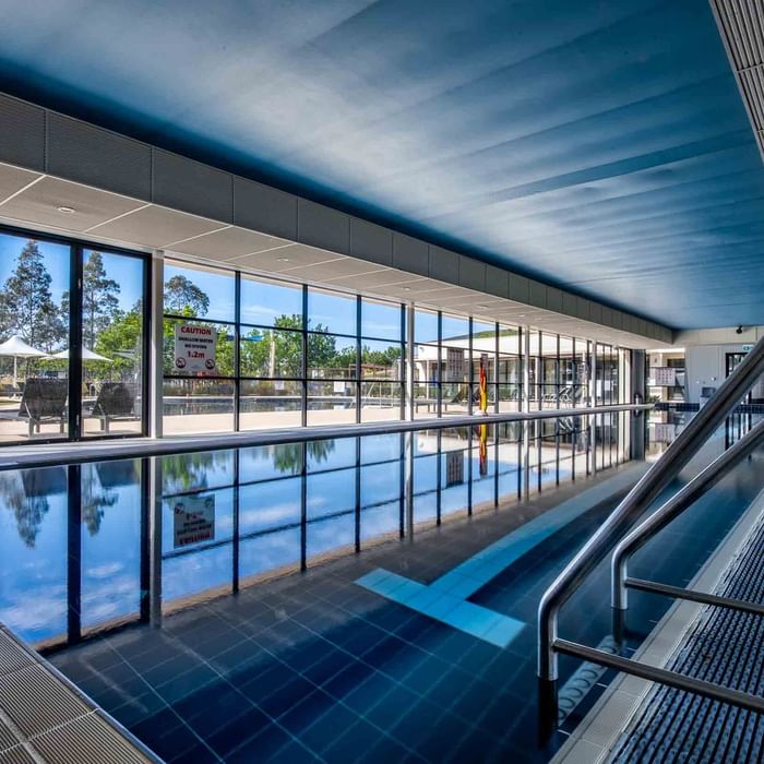 Indoor lap pool with reflective water, and large windows at Mercure Kooindah Waters