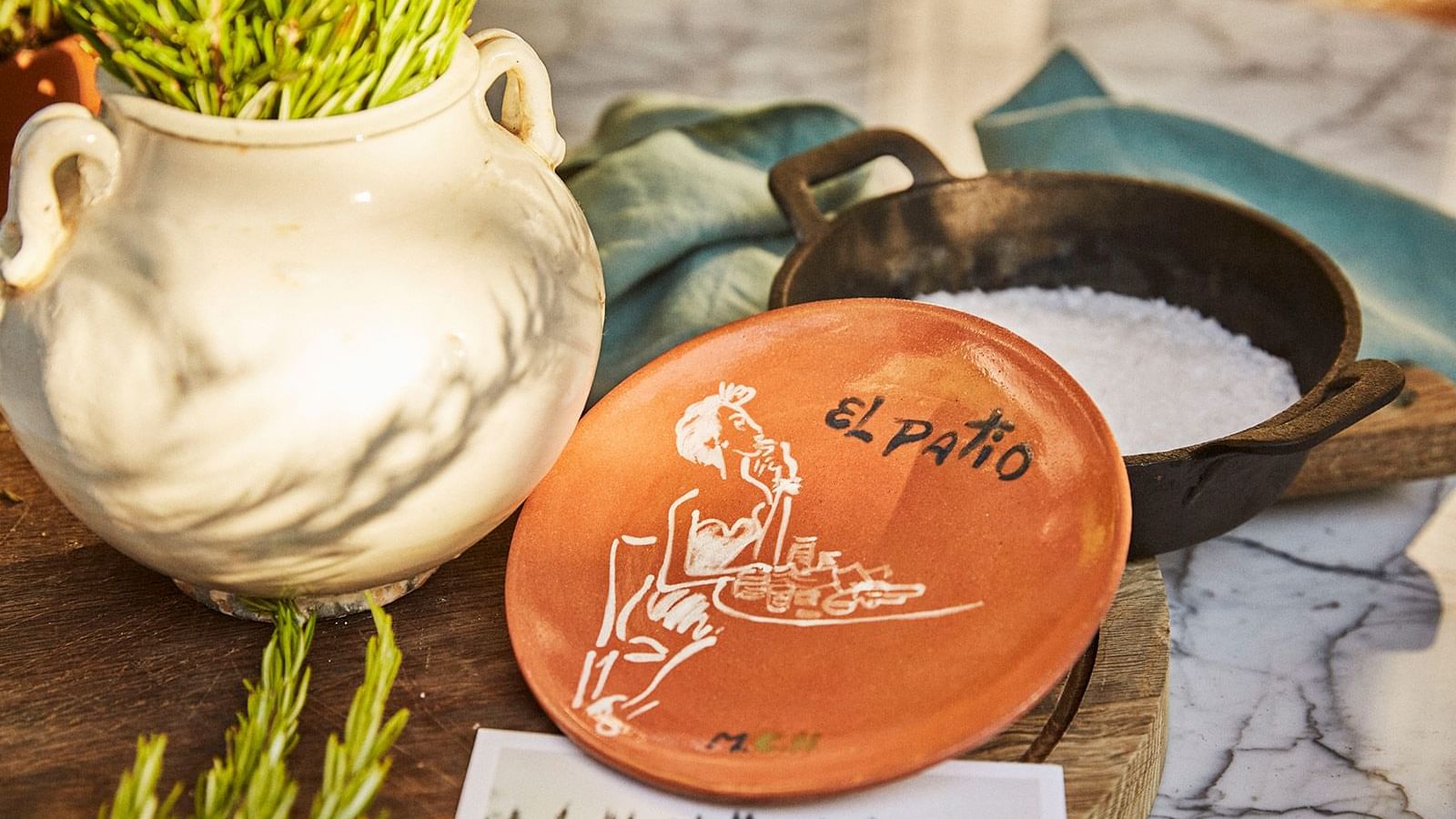 Hand-painted terra cotta plate for El Patio resting on a marble surface near a clay pot at Marbella Club