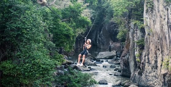 Lady zip lining over the river alongside the forest near Hotel Rio Perdido