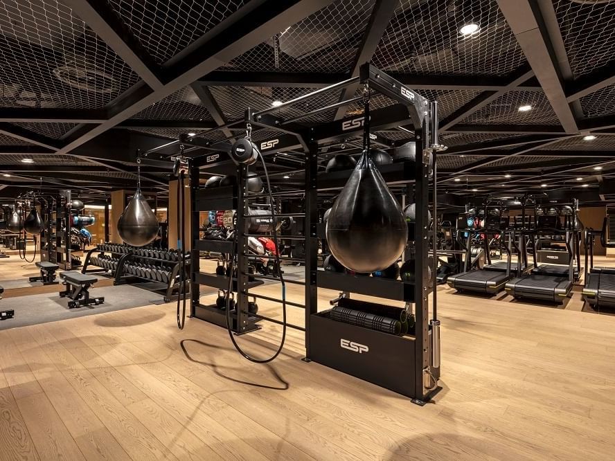 Well-equipped modern gym featuring punching bags, weights, and treadmills at The Londoner Hotel