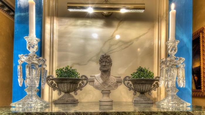 Chandeliers en cristal et buste romain ancien sur table de marbre.