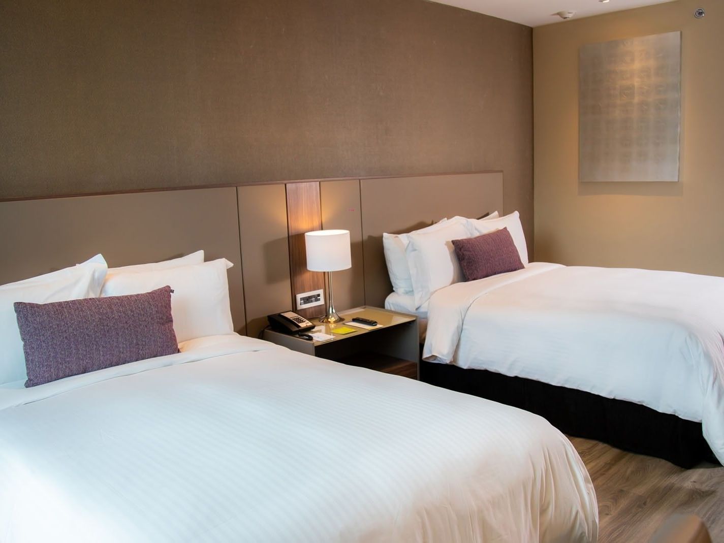 Deluxe Luxury King twin room with two white beds, warm lighting, and wooden floors at Camino Real Fashion Drive, Monterrey