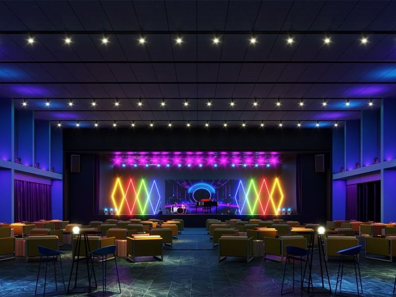 Gran escenario de teatro en Fiesta Americana Funeeq Punta Cana con luces geométricas de neón y asientos cómodos