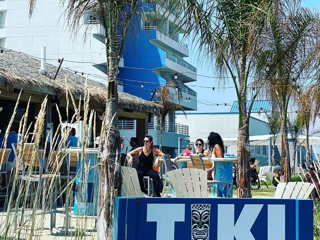tiki Bar sign and woman having drinks outside