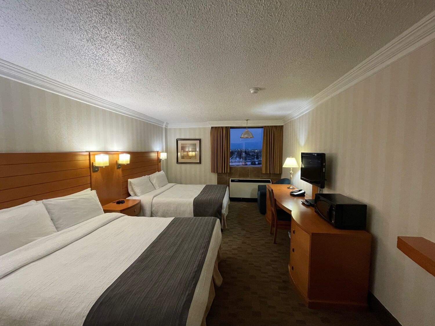 Two beds and work area with TV in illuminated Garden Standard at The Glenmore Inn & Convention Centre