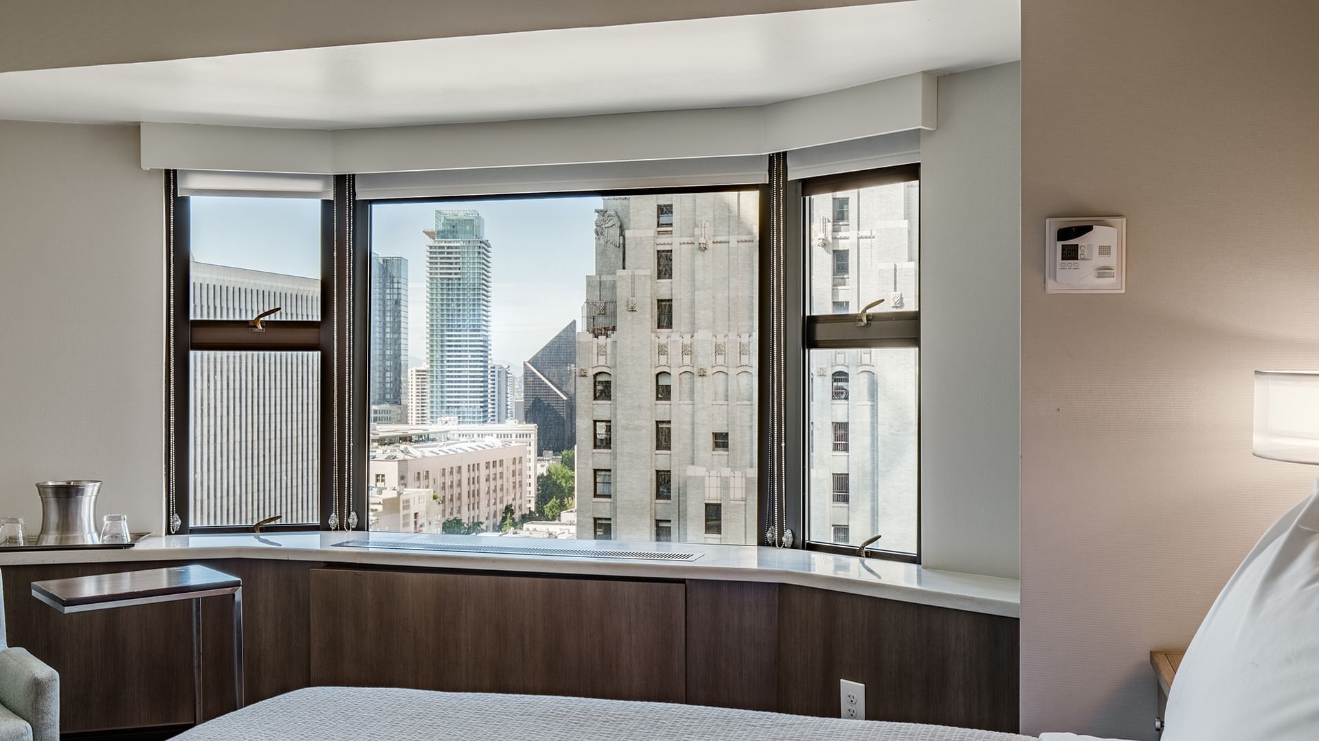 A hotel room with a king-sized bed and a large window overlooking the city.