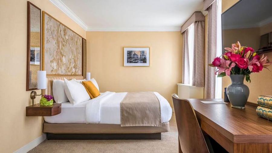 Executive King with a striped bed, floral art, and a wooden desk at Warwick Allerton Chicago