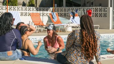 Guests socializing in the outdoor pool with colorful lounge chairs in the background at Bardstown Motor Lodge