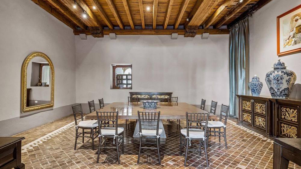 Formal meeting room with a large wooden table, blue patterned vases, and a beamed ceiling at Quinta Real Puebla