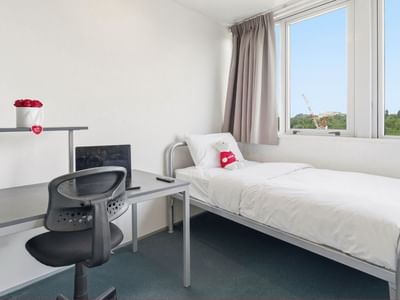Neat room with bed, desk, chair, and window at Student Living Auckland Anzac.