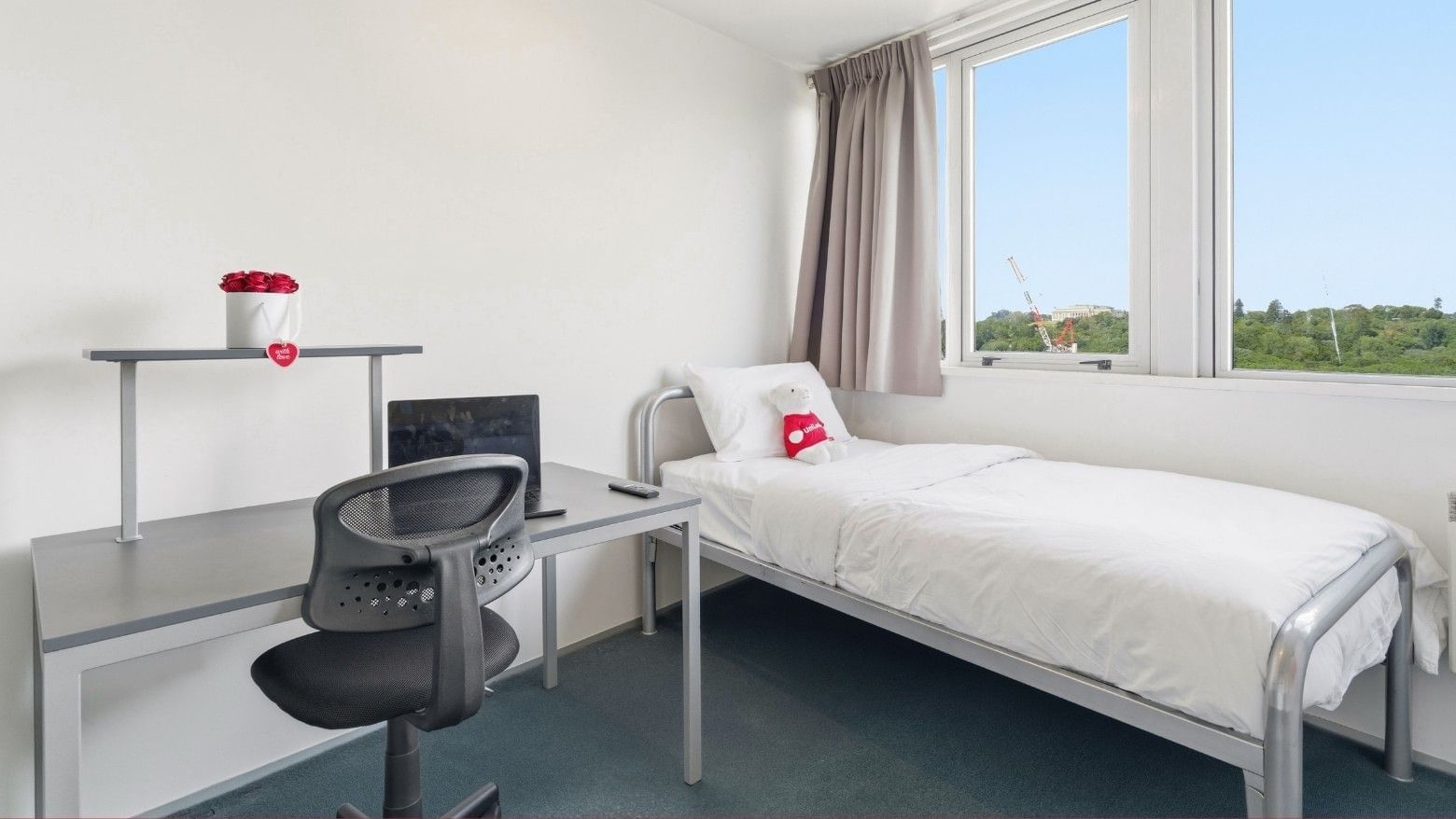 Neat room with bed, desk, chair, and window at Student Living Auckland Anzac.
