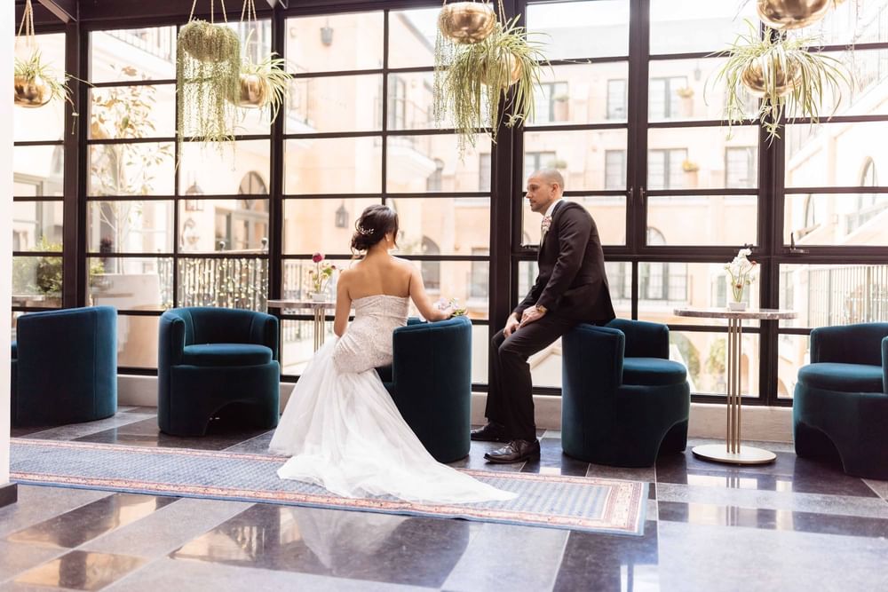 Newlywed couple relaxing in a stylish lounge area by the windows at El Prado Hotel