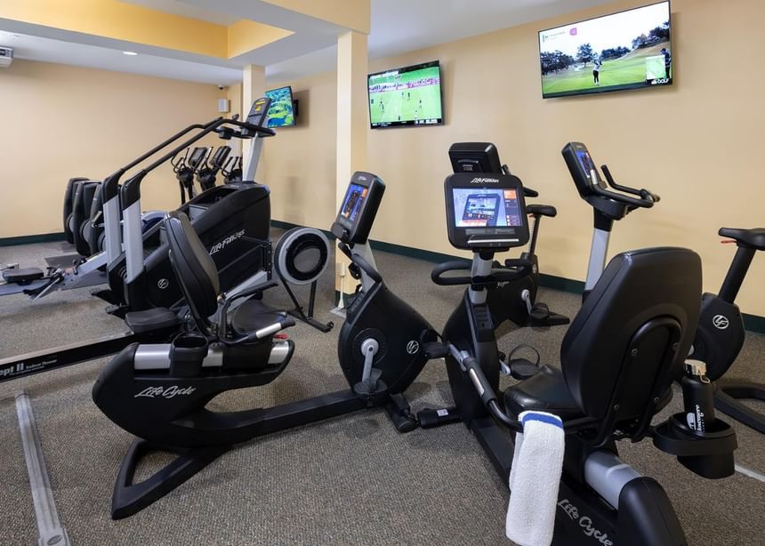 Stationary bikes, treadmills & fitness training equipment facing wall-mounted TVs in Ogunquit Fitness Center near Meadowmere Resort