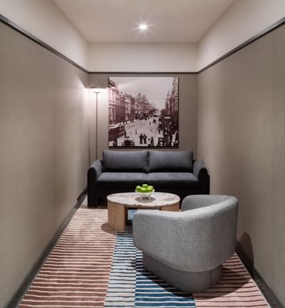 Cozy lounge with a gray sofa, armchair, and a small wooden table with green apples at Amora Herencia Riverwalk Melbourne