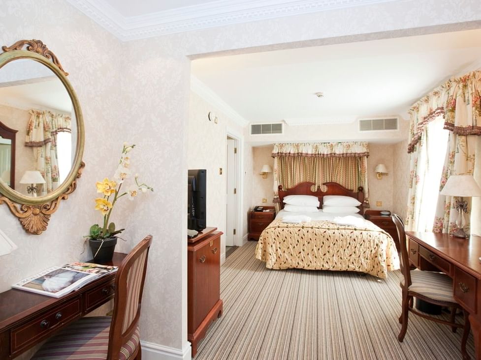 Elegant Brampton Lodge Suite at Marygreen Manor, with a plush bed, wall mirror, desks, and traditional wooden furniture
