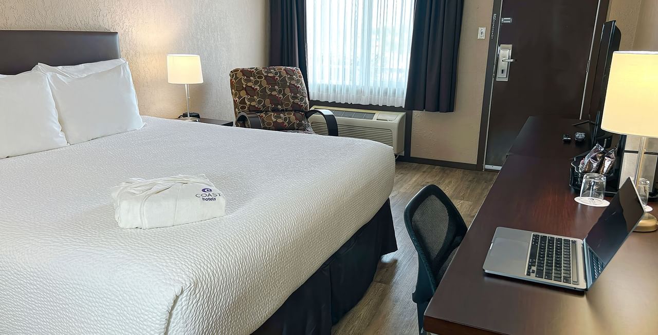 Hotel room with bed, table, TV, lamp, and chairs