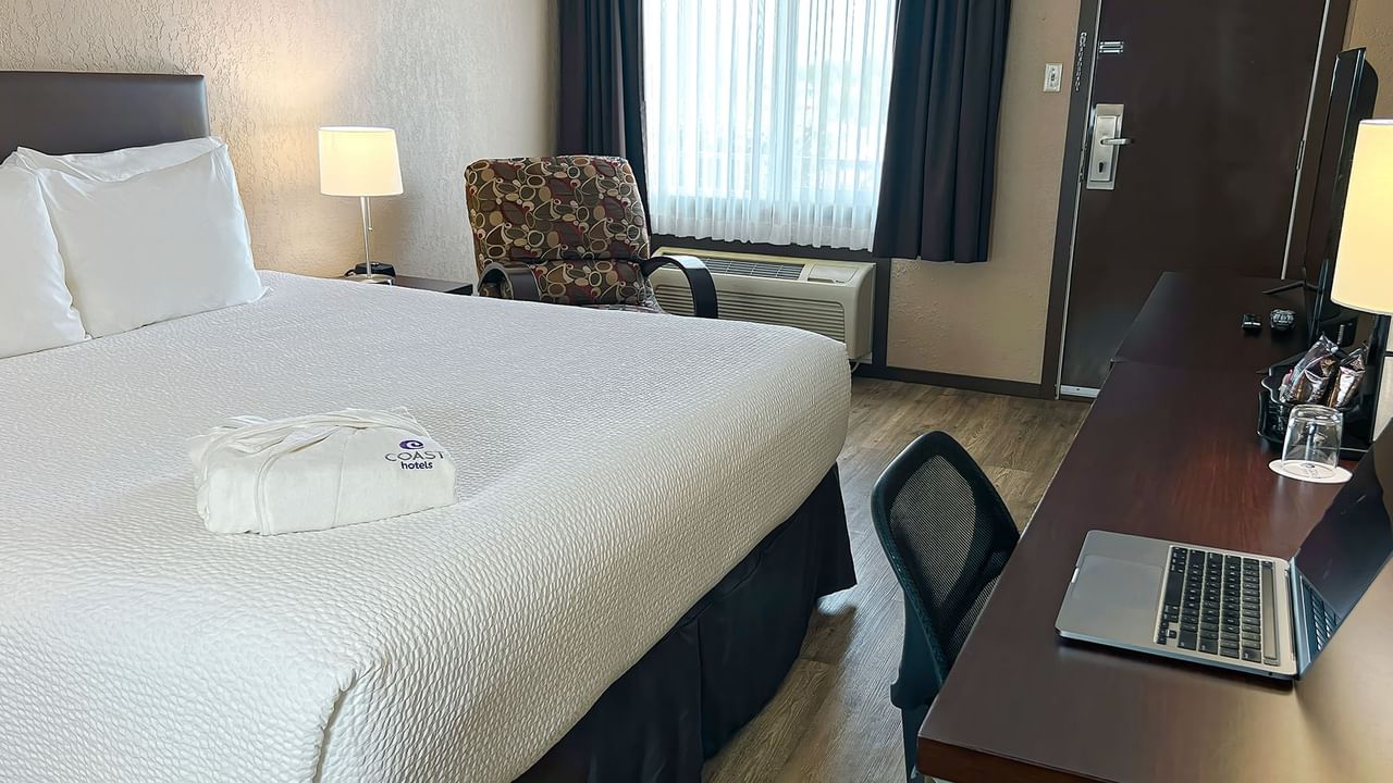 Bed, chair, desk, bath robe in a hotel room