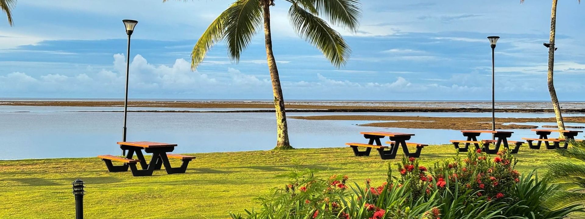 Tropical outdoor seating area with picnic tables and lush greenery at The Naviti Resort in Korolevu