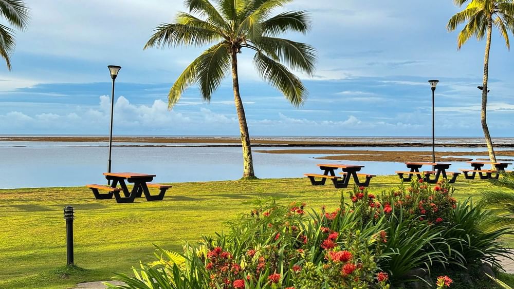 Tropical outdoor seating area with picnic tables and lush greenery at The Naviti Resort in Korolevu.