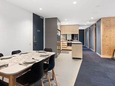 La Trobe University - North and South Apartments modern dining area with blue carpet and sleek kitchen.