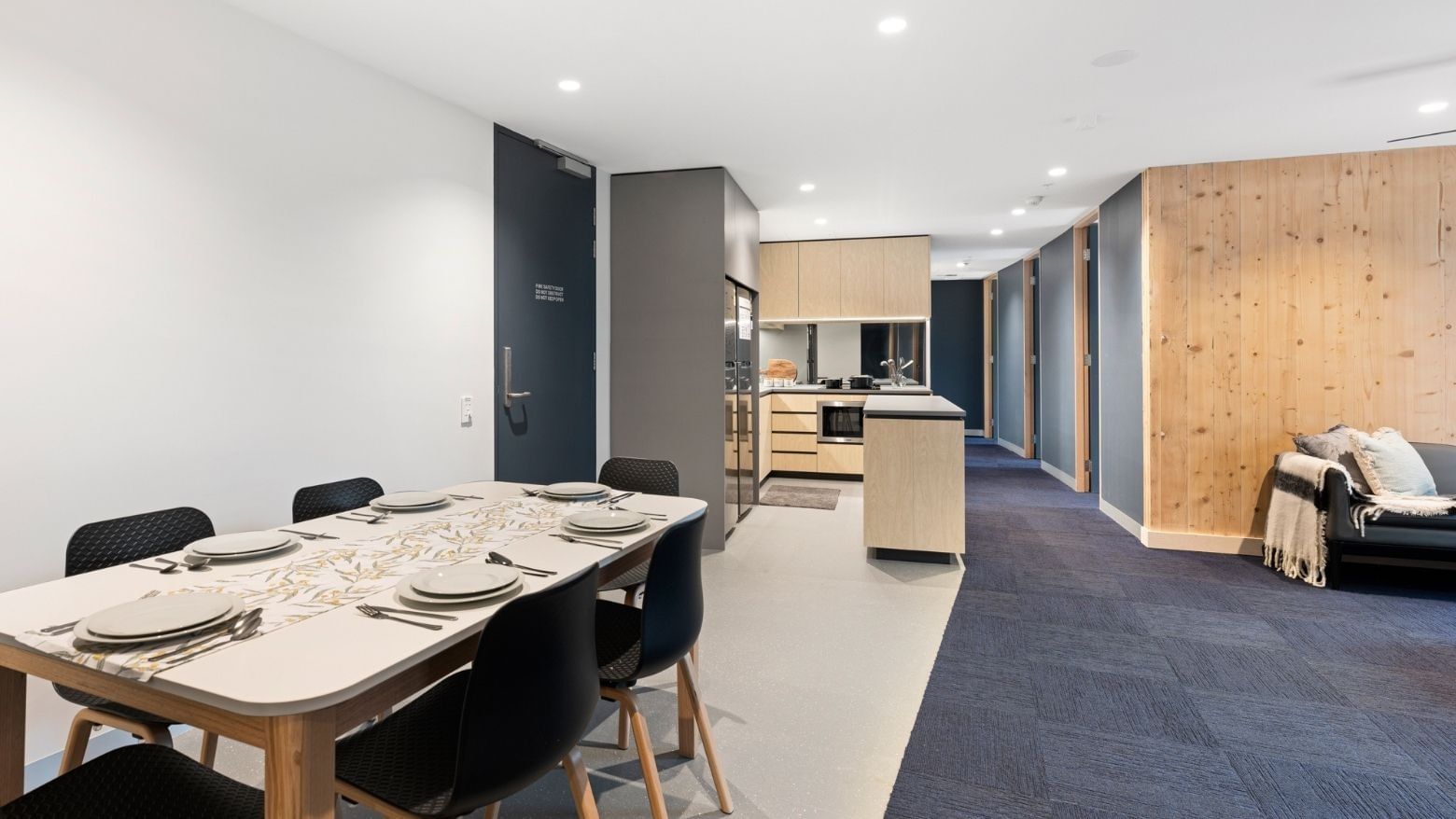 La Trobe University - North and South Apartments modern dining area with blue carpet and sleek kitchen.