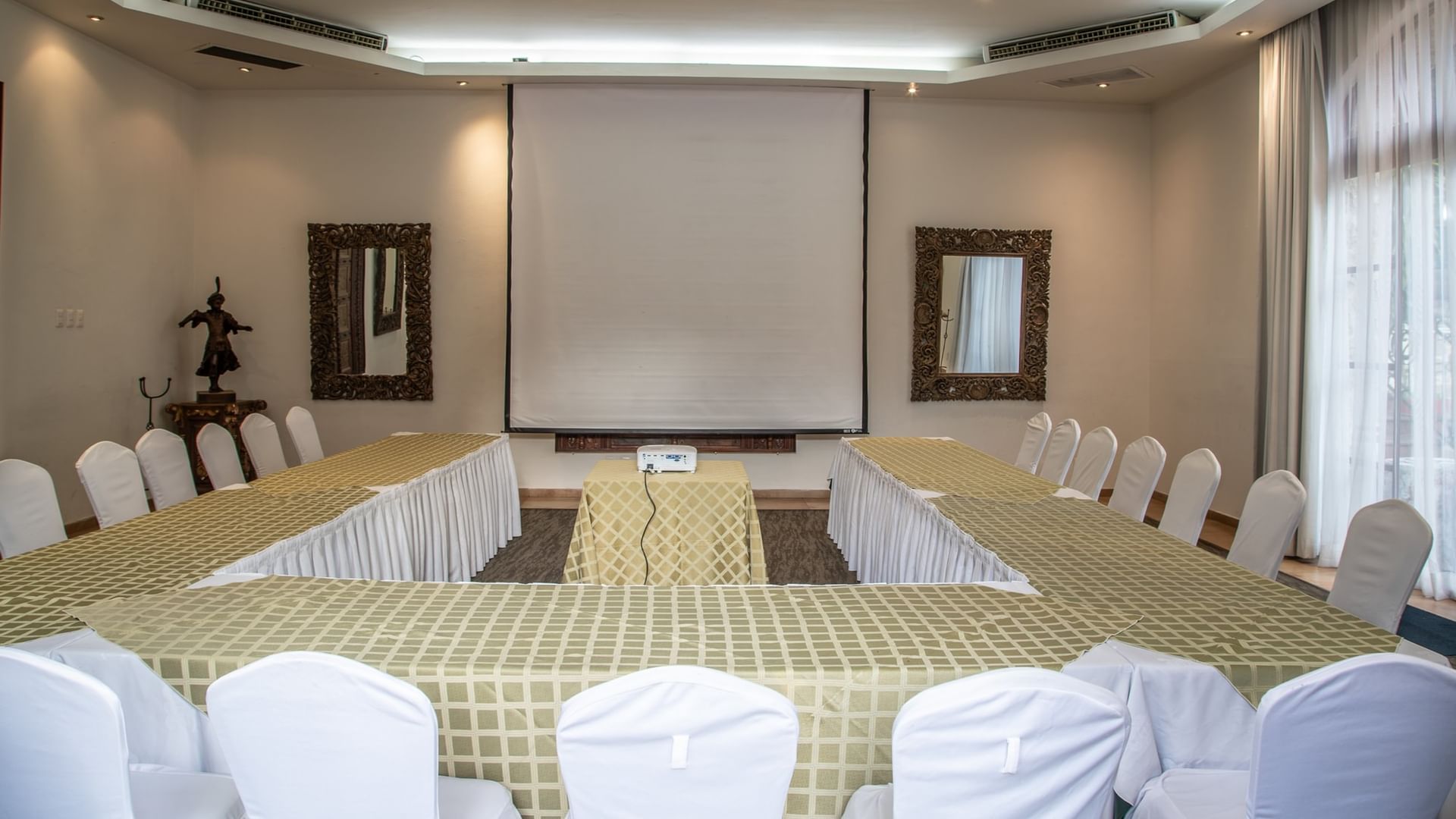 Salón Cuatro Estaciones con mesas en forma de U, pantalla de proyección y sillas blancas en Quinta Real Guadalajara
