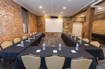 U-shaped table set-up with projector screen in Savannah Meeting Spaces at River Street Inn