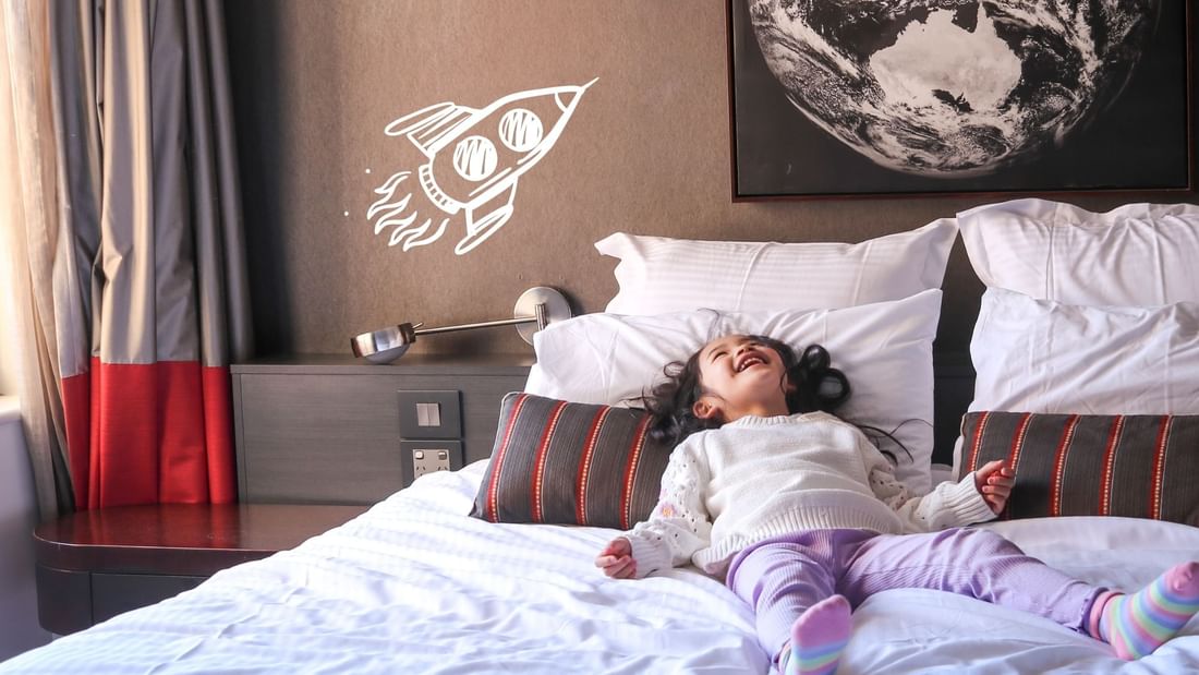 Little girl relaxing on a hotel bed at Pullman Mercure Melbourne Albert Park