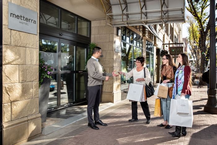 Three women with shopping bags and a man converse outside the Metterra Hotel on Whyte on a sunny day.