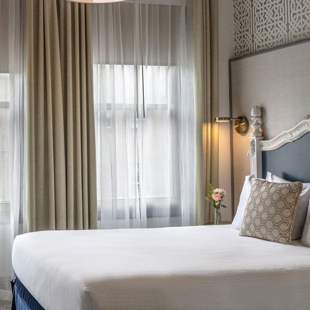 Round table by a white chair and tan curtains under a hanging lamp in Deluxe Queen Room at Warwick San Francisco