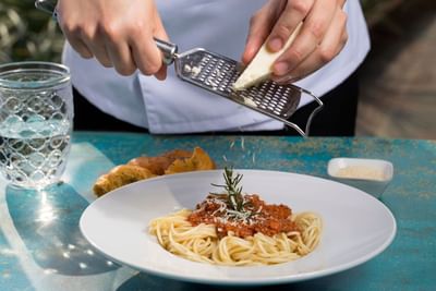 Chef grating cheese on a pasta plate at Porta Hotel Del Lago