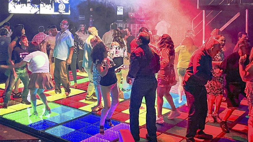 Multitud bailando en una pista LED multicolor durante un evento en El Rollo de Araiza Palmira