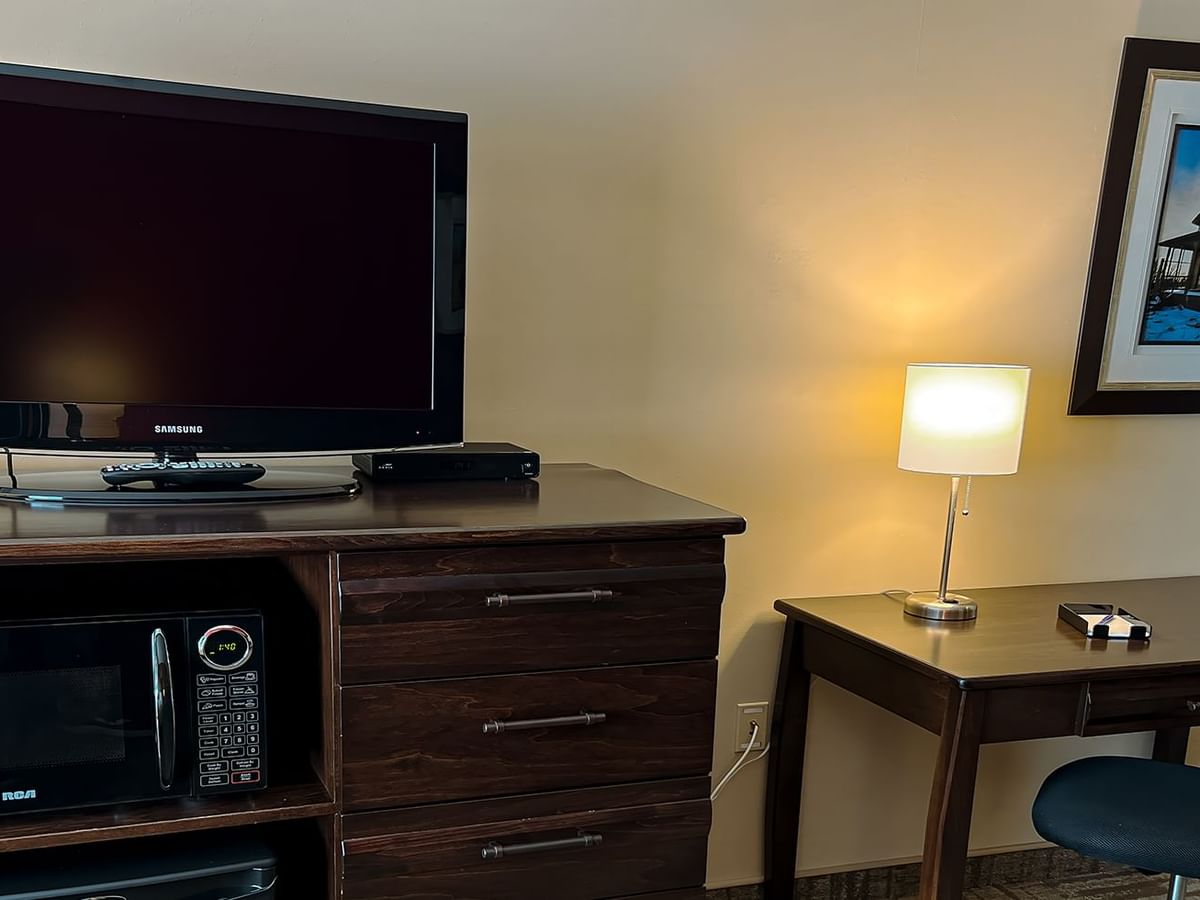 Chair, desk, painting, lamp, drawers, and a TV