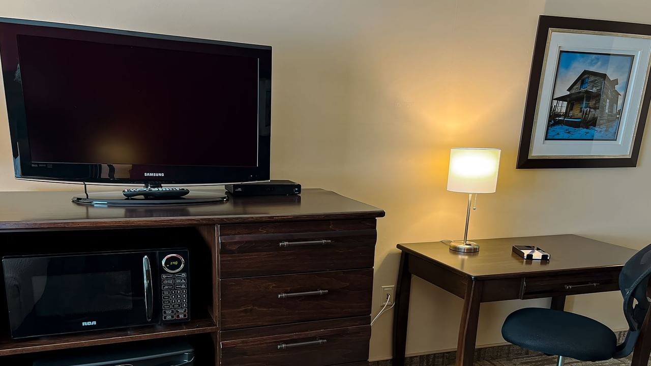 Chair, desk, painting, lamp, drawers, and a TV