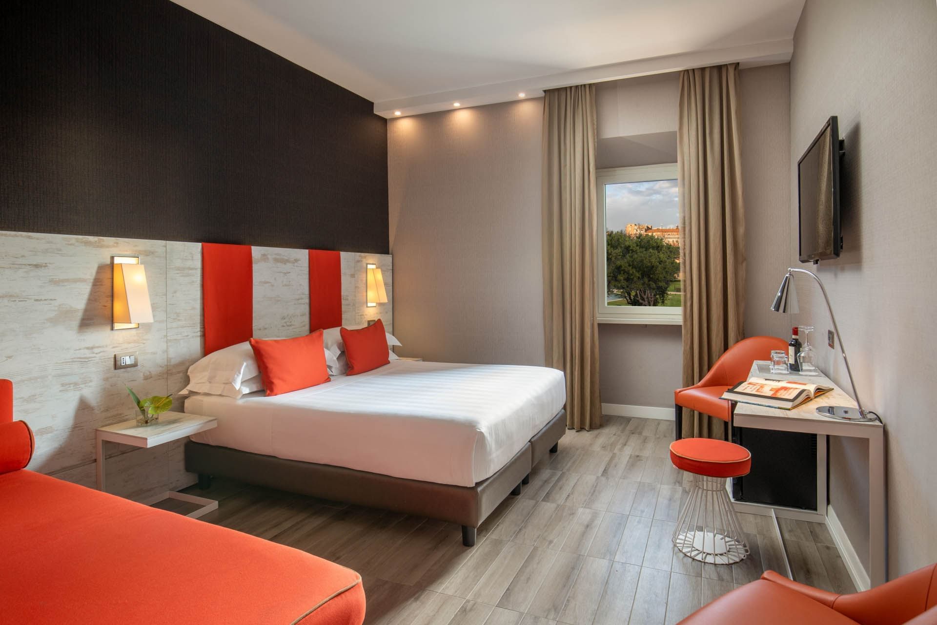 Bright Deluxe Room at The Guardian Hotel with a comfy bed, work area, and a view of greenery outside