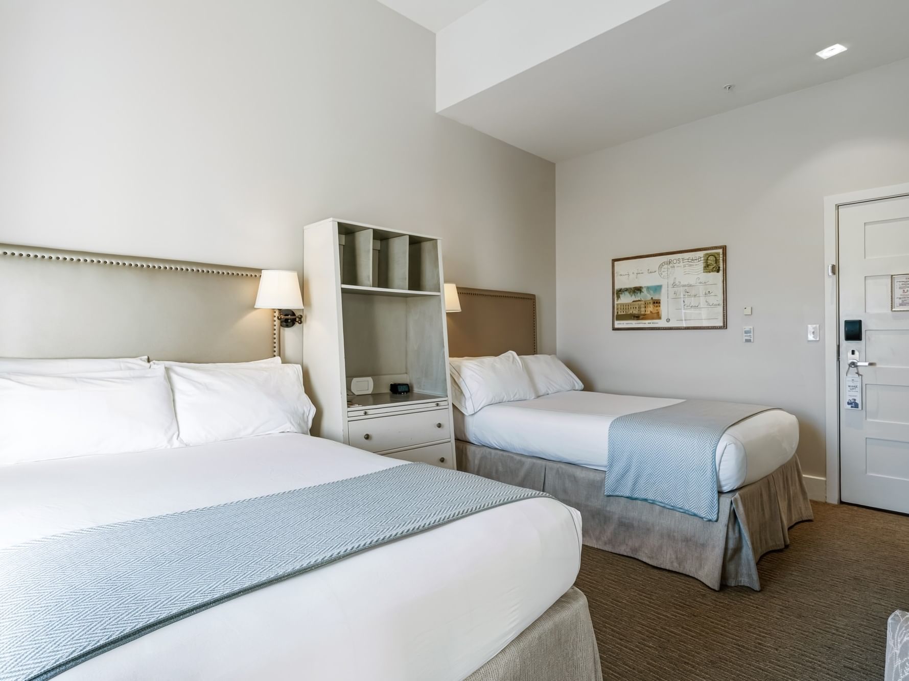 Two neatly made beds with blue blankets in a Deluxe Double room at Hotel Parq Central, Albuquerque.