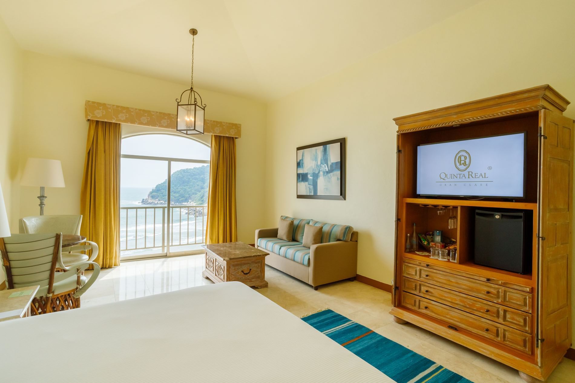 Hotel room with a blue striped sofa and a private balcony overlooking the ocean at Quinta Real Acapulco