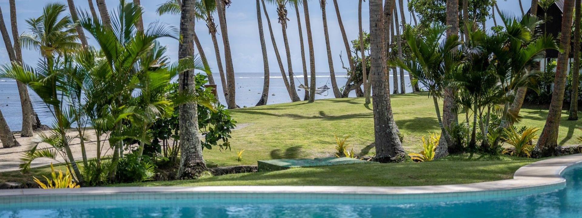 Clear pool surrounded by palm trees and lush greenery at Tambua Sands Beach Resort in Sigatoka