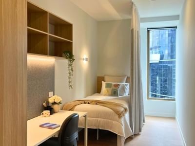 A cozy room with a bed, desk, and window within a 4 Bedroom Twin Share Apartment at UniLodge Brisbane City.