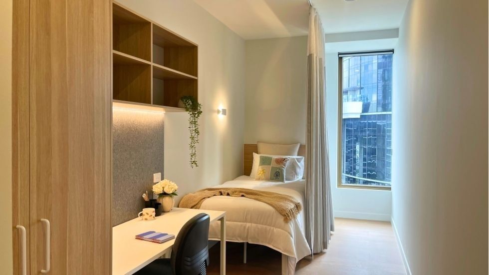 A cozy room with a bed, desk, and window within a 4 Bedroom Twin Share Apartment at UniLodge Brisbane City.