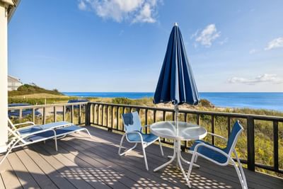 Loungers & an umbrella on the balcony with a sea view in Oceantide Beachfront King Efficiency at Chatham Tides Resort