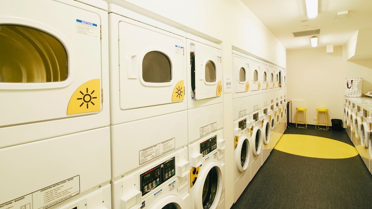 Row of white washers and dryers in a clean, bright laundry room at La Trobe University Menzies College.
