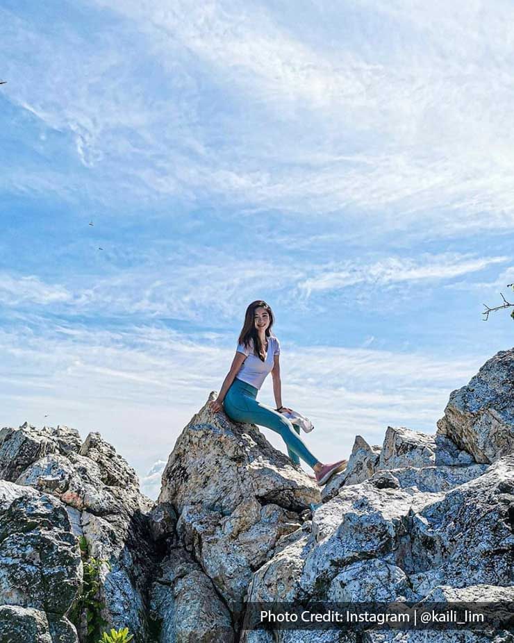 Lady sitting on a rocky cliff posing for a photo - Lexis Port Dickson