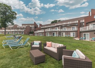 Lawn chairs adorned with picnic tables and plush seating on a greenery ground by Ogunquit River Inn